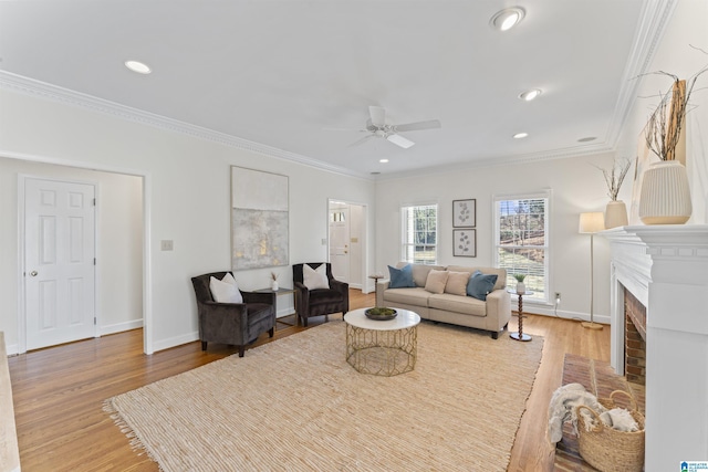 living room with recessed lighting, a fireplace, baseboards, light wood-style floors, and crown molding