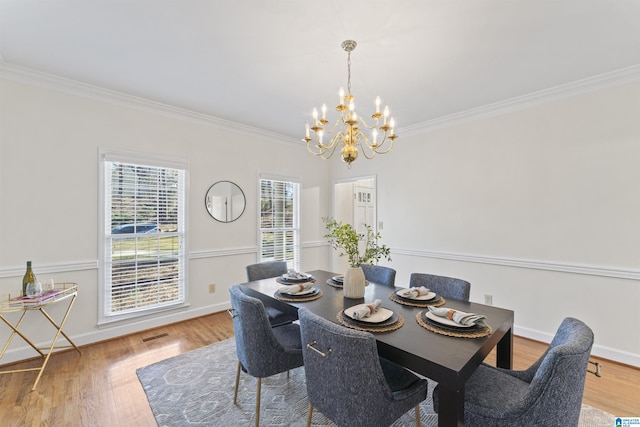 dining area featuring ornamental molding, an inviting chandelier, wood finished floors, and baseboards