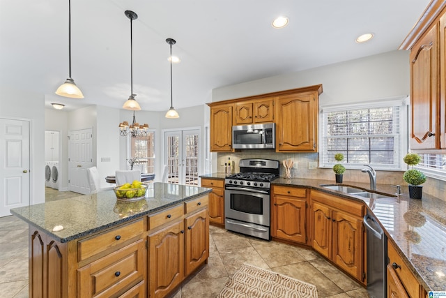 kitchen featuring stainless steel appliances, brown cabinets, a sink, and backsplash