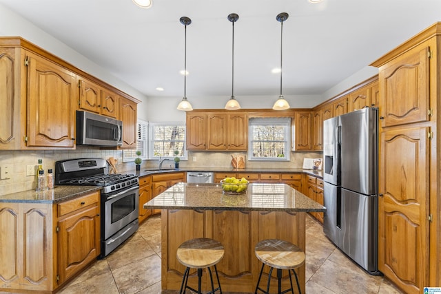 kitchen with a breakfast bar, brown cabinets, tasteful backsplash, appliances with stainless steel finishes, and a kitchen island