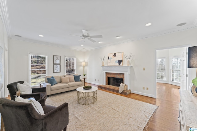 living area featuring recessed lighting, a fireplace, baseboards, light wood finished floors, and crown molding