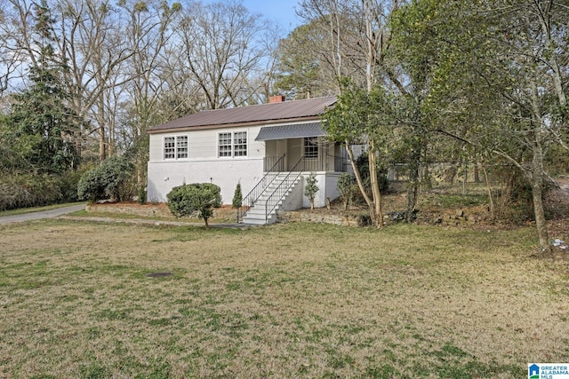 single story home featuring stairway, metal roof, a chimney, and a front lawn