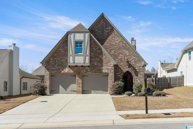 english style home with a garage, concrete driveway, brick siding, and a chimney