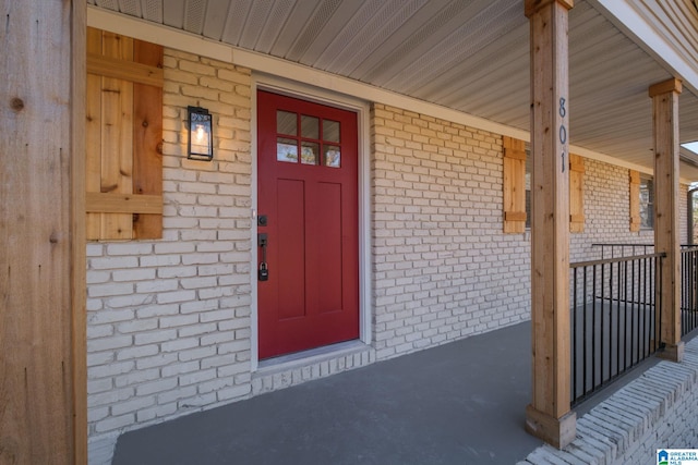 property entrance featuring a porch and brick siding