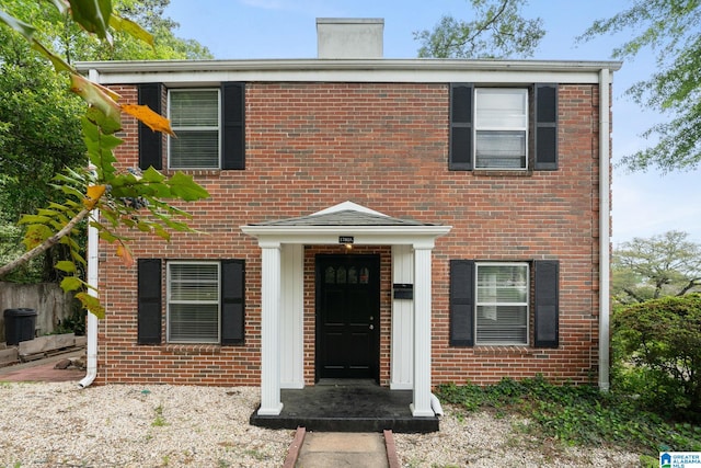 view of front of home with brick siding and a chimney