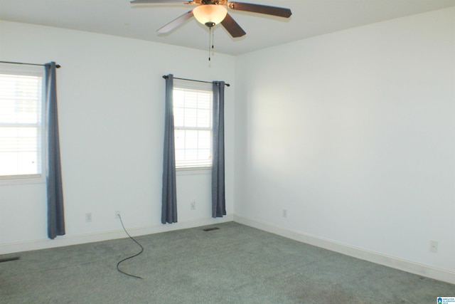 empty room with a ceiling fan, light colored carpet, visible vents, and baseboards