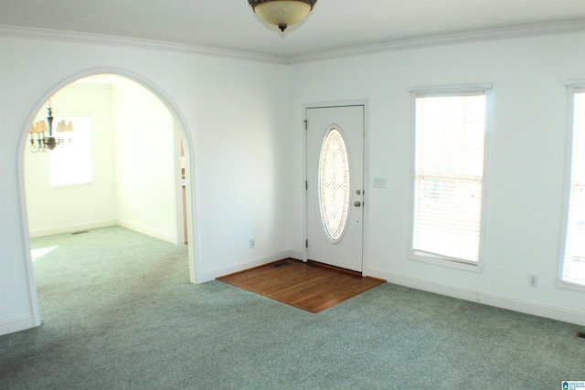 entryway with baseboards, carpet, arched walkways, and crown molding