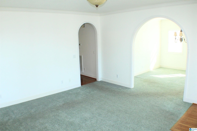 carpeted spare room with baseboards, visible vents, arched walkways, and ornamental molding