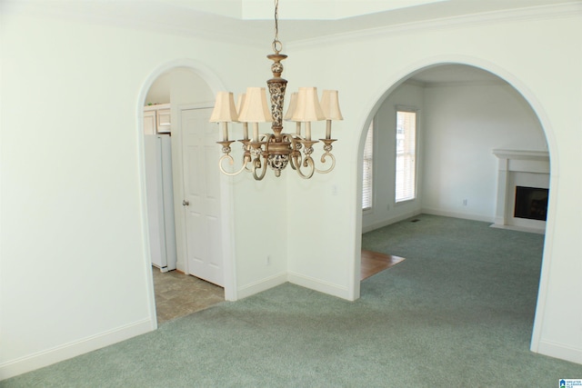 unfurnished dining area featuring a fireplace with flush hearth, light colored carpet, crown molding, and baseboards