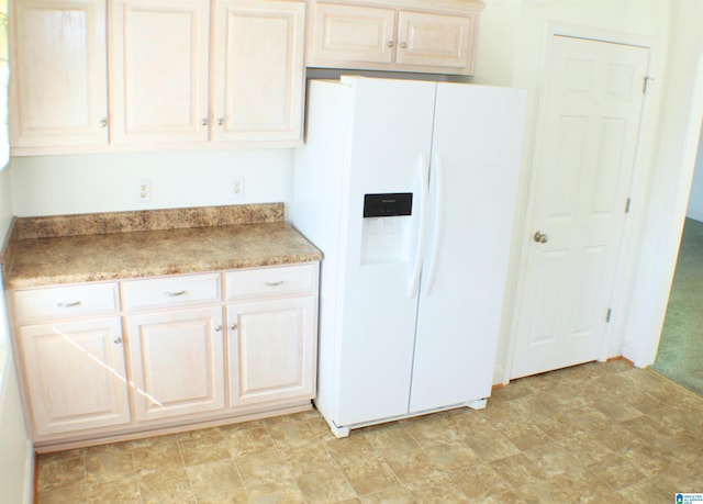 kitchen featuring stone finish flooring and white fridge with ice dispenser