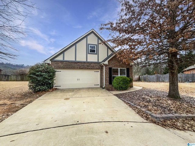 tudor-style house featuring brick siding, driveway, fence, and stucco siding