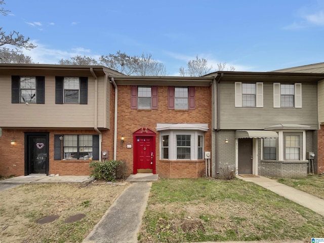 view of property with a front yard and brick siding