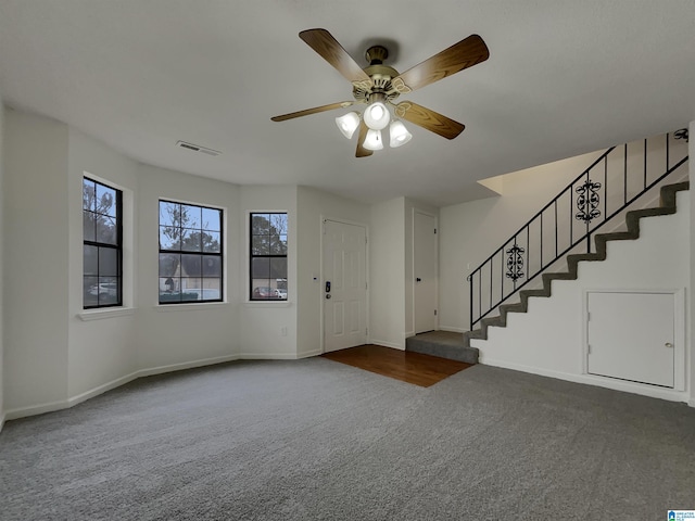 carpeted foyer entrance featuring stairs, ceiling fan, visible vents, and baseboards