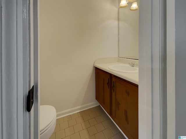 bathroom with toilet, vanity, and baseboards