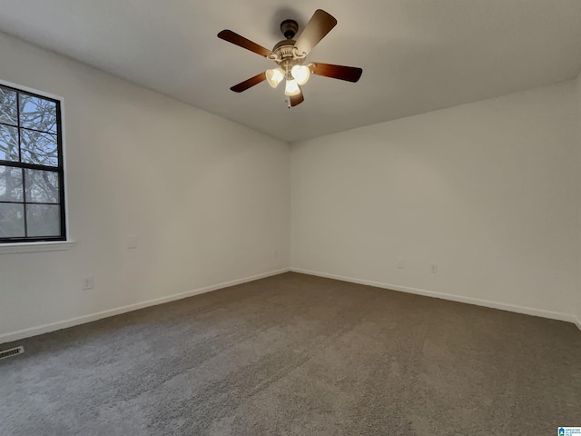 empty room with ceiling fan, dark carpet, and baseboards