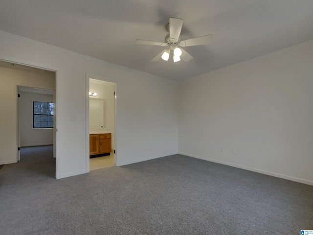 unfurnished bedroom featuring crown molding, dark carpet, ensuite bathroom, ceiling fan, and baseboards