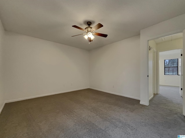 empty room with ceiling fan, carpet flooring, attic access, and baseboards