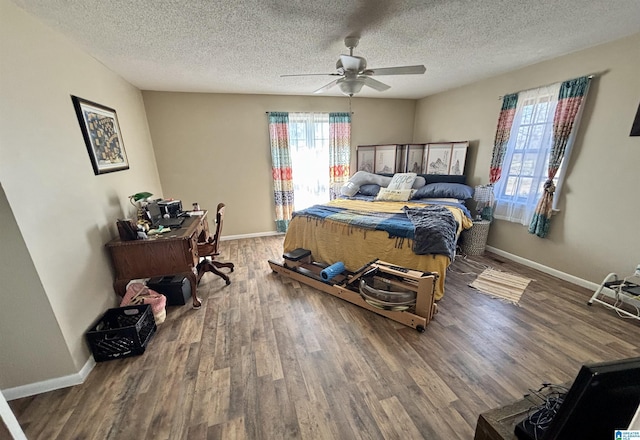 bedroom with a textured ceiling, baseboards, and wood finished floors