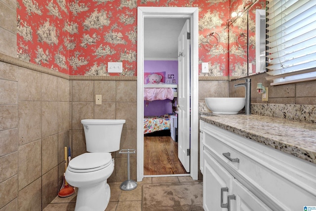 ensuite bathroom featuring wallpapered walls, toilet, a wainscoted wall, ensuite bathroom, and vanity