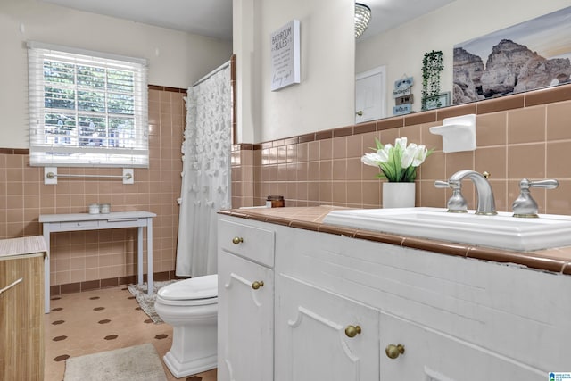 full bathroom with tile walls, toilet, wainscoting, vanity, and tile patterned flooring