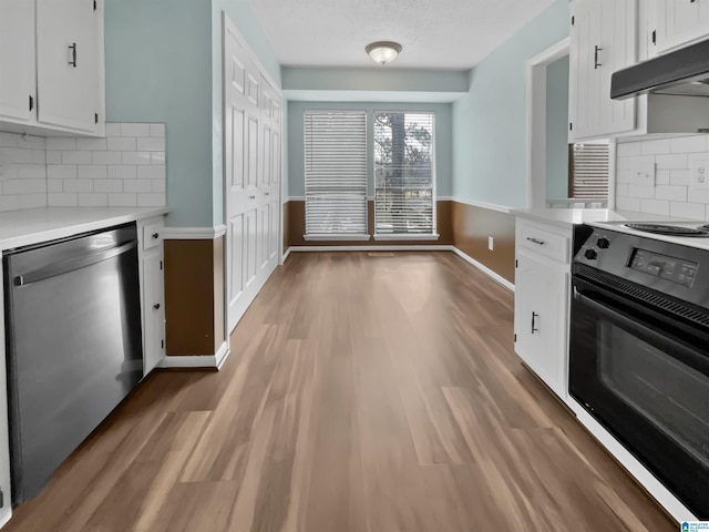 kitchen with light countertops, stainless steel dishwasher, white cabinetry, range, and under cabinet range hood