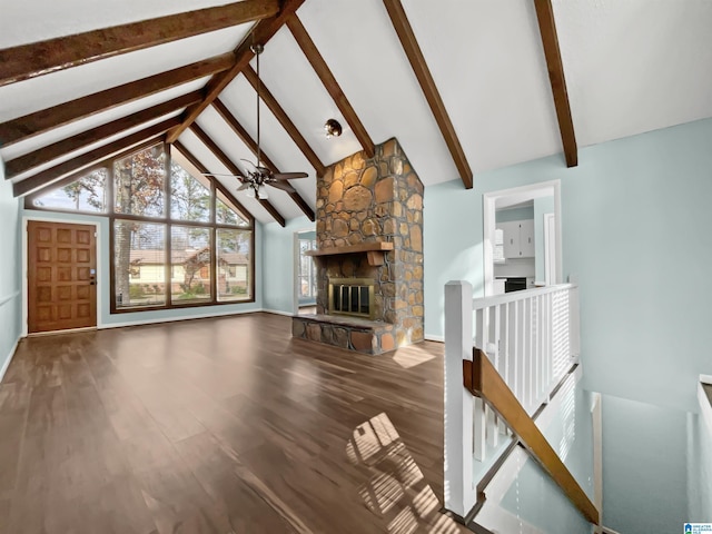 unfurnished living room featuring ceiling fan, a stone fireplace, wood finished floors, high vaulted ceiling, and beamed ceiling