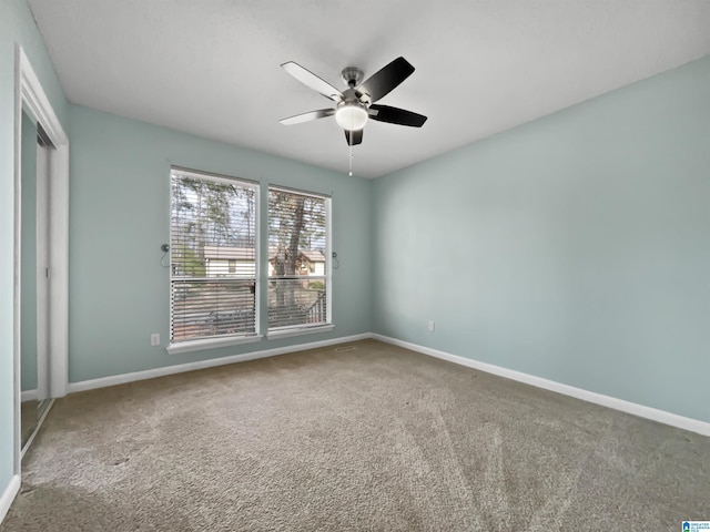 carpeted empty room with ceiling fan and baseboards