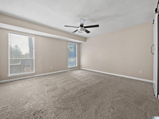 unfurnished room featuring carpet floors, ceiling fan, baseboards, and a textured ceiling