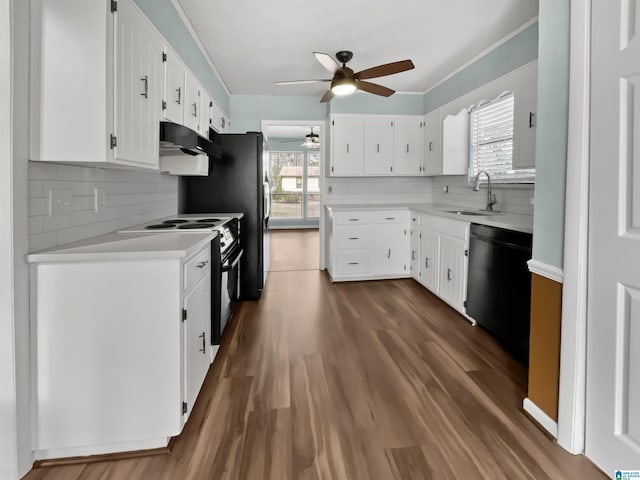 kitchen with dark wood finished floors, light countertops, a sink, under cabinet range hood, and black appliances