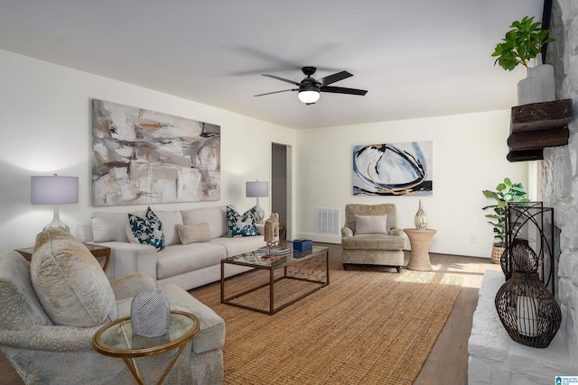 living room featuring visible vents, ceiling fan, baseboards, and wood finished floors