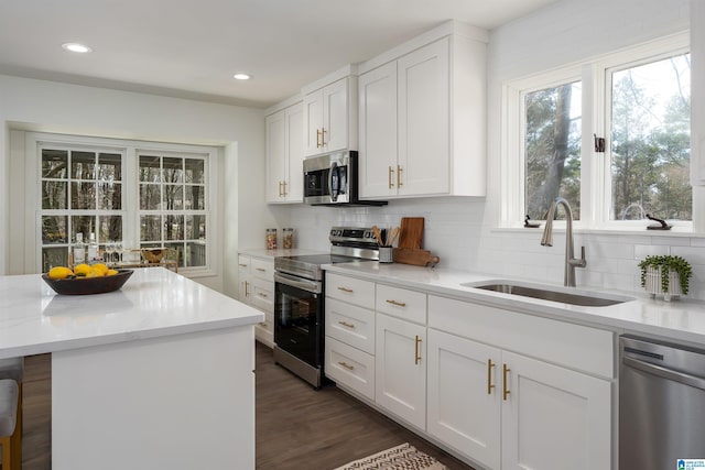 kitchen with appliances with stainless steel finishes, backsplash, a sink, and white cabinets