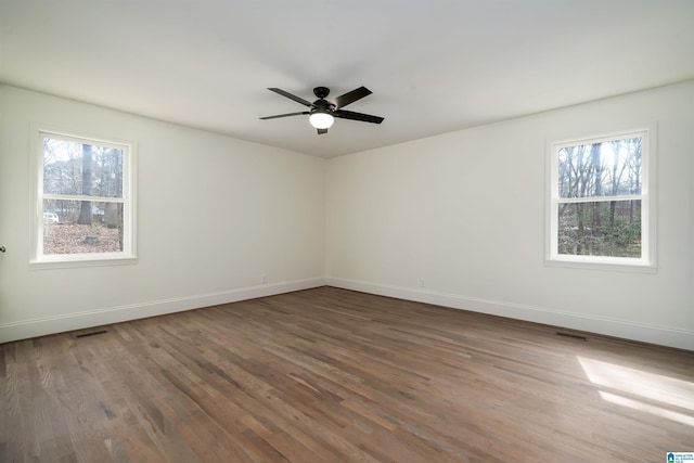 spare room with a ceiling fan, visible vents, baseboards, and wood finished floors