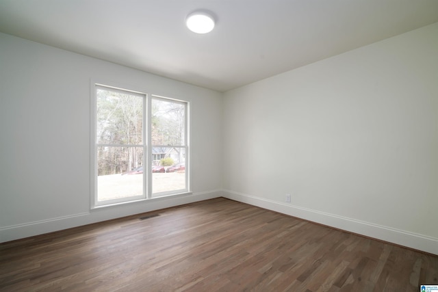 unfurnished room with visible vents, baseboards, and wood finished floors