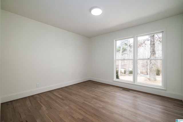 unfurnished room with visible vents, baseboards, and wood finished floors