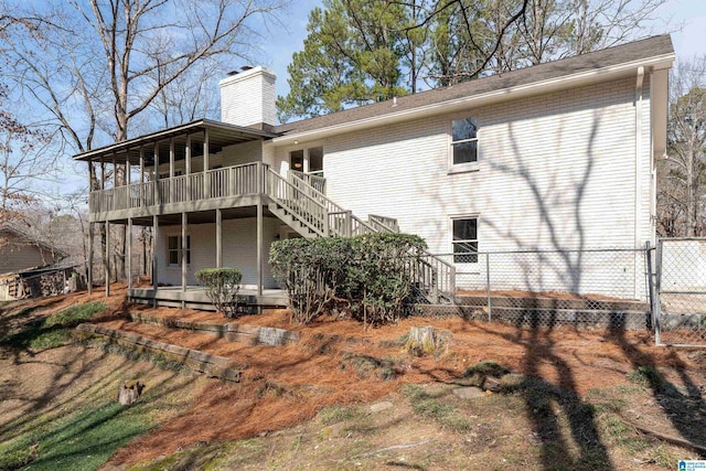 back of property featuring stairs, brick siding, a chimney, and fence