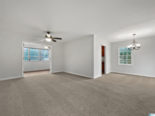 carpeted spare room with baseboards and ceiling fan with notable chandelier