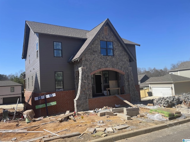 view of front of house featuring a shingled roof, stone siding, brick siding, and a garage