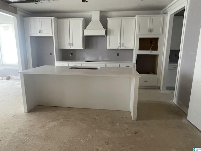 kitchen featuring custom exhaust hood, white cabinets, unfinished concrete flooring, and a center island