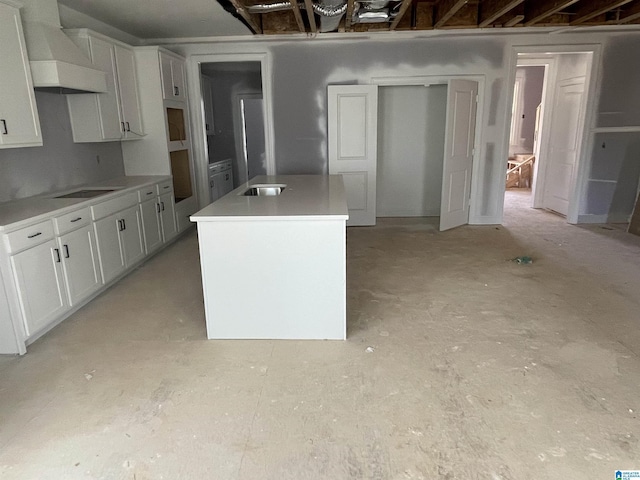 kitchen with black electric cooktop, premium range hood, white cabinets, light countertops, and a center island