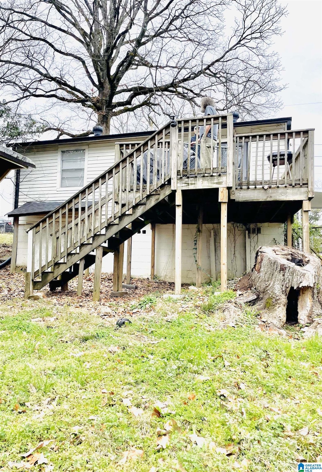 view of side of home featuring stairs, a deck, and a lawn