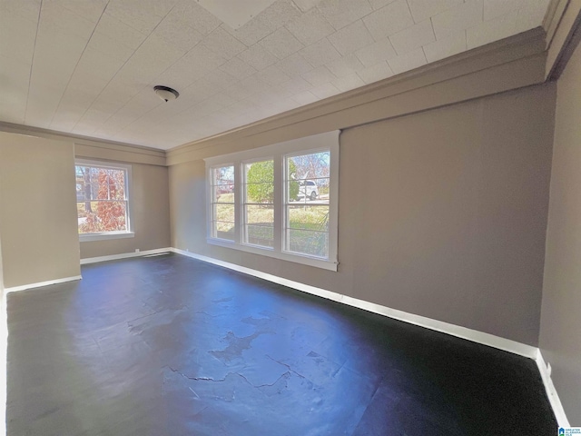 spare room featuring concrete flooring, ornamental molding, and baseboards