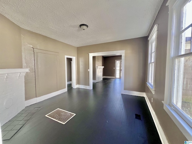 empty room with dark wood finished floors, a textured ceiling, and baseboards