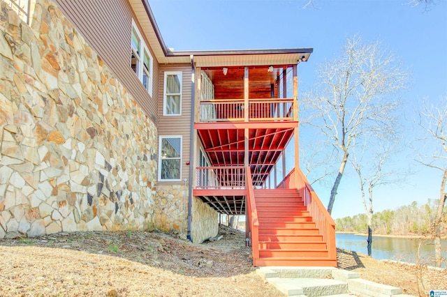 exterior space with stairs, stone siding, and a water view