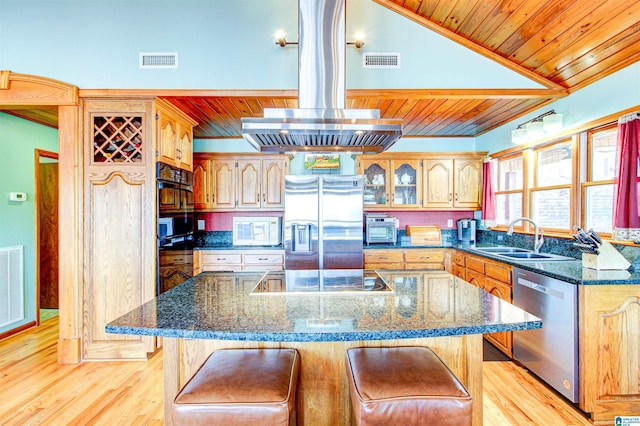 kitchen featuring a center island, stainless steel appliances, visible vents, a sink, and a kitchen bar