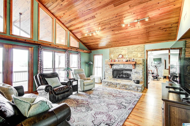 living room featuring high vaulted ceiling, wooden ceiling, a stone fireplace, and light wood finished floors