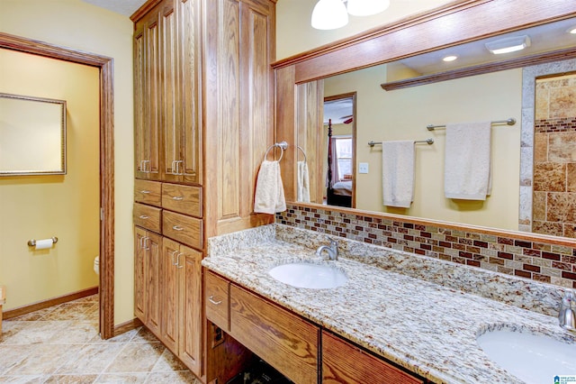 ensuite bathroom with toilet, connected bathroom, backsplash, and a sink