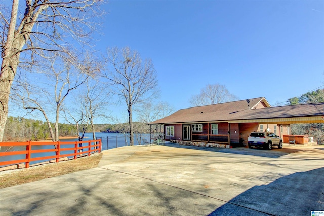 view of front of house with driveway, a water view, and fence