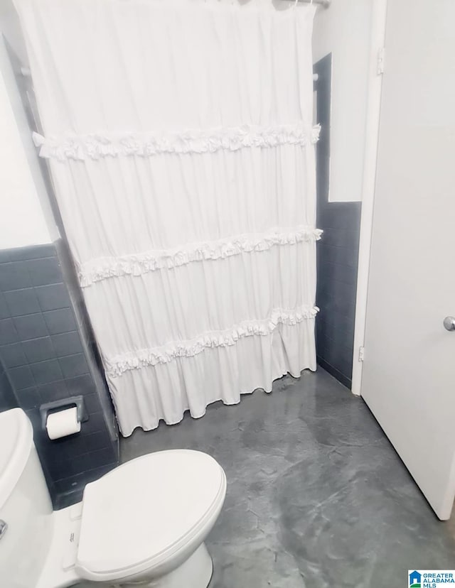 1525 NW Ridge St, Cullman, AL 35055 - full bathroom with a shower with shower curtain, concrete flooring, toilet, and tile walls