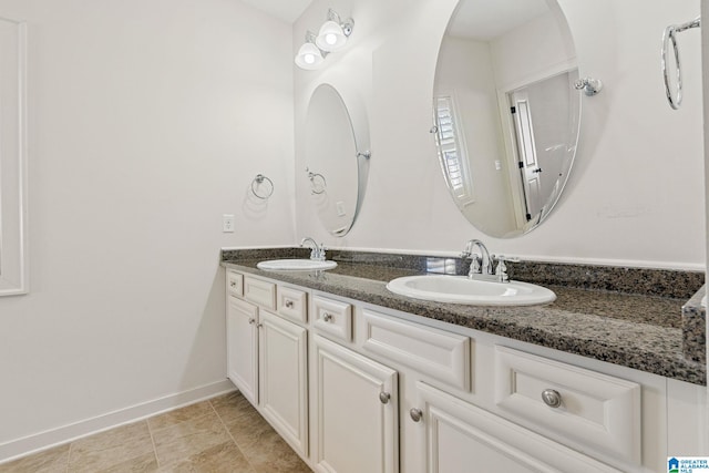 bathroom featuring a sink, baseboards, and double vanity