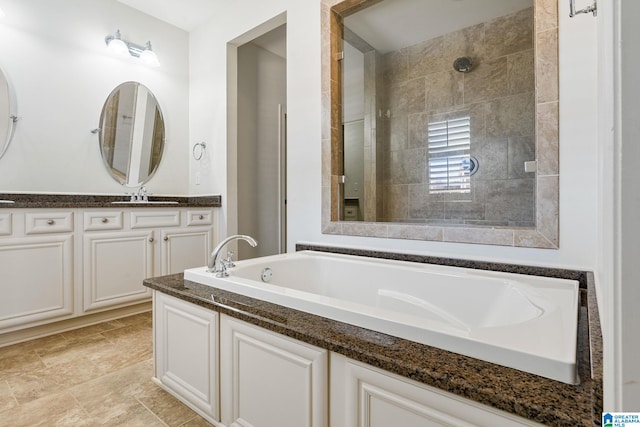 bathroom with tiled shower, vanity, and a bath